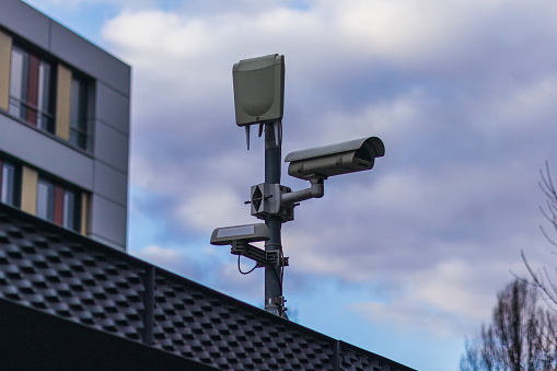A security camera on a mast in front of a company building, showing the security needs.